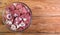 Boneless lamb steak cut into pieces, meat in a glass bowl on a wooden table, top view