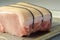 Boneless pork loin joint tied with string on the oven tray, raw meat prepared for baking