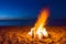 Bonfire. Small campfire with gentle flames beside a lake during a glowing sunset. San Juan night on the beach.