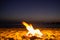 Bonfire. Small campfire with gentle flames beside a lake during a glowing sunset. San Juan night on the beach.