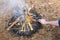 Bonfire in the spring forest on the background of withered grass. In the frame of the hand of a man.