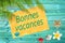 Bonnes vacances (meaning happy summer) written on a paper on colorful wood background with palm trees