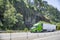Bonnet bright green big rig semi truck with high roof cab transporting cargo in reefer semi trailer driving on the awesome highway