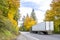 Bonnet long haul big rig blue semi truck transporting cargo in reefer semi trailer driving on the autumn highway road with green