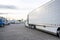 Bonnet white big rig semi truck transporting cargo in reefer semi trailer driving on the truck stop parking lot looking for empty