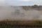 BONNYVILLE, ALBERTA, CANADA - SEPTEMBER 10, 2020: A local farmer in John Deere tractor works in a cloud of dust as he