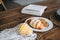 Book and croissant with cookies on a wooden kitchen table. Domestic life