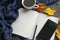 A book with a Cup of tea and a mobile phone surrounded by autumn leaves on a grey background