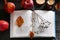 Book with dried flower, leaves as bookmark, ripe apples and candle on wooden table, above view