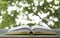 Book on wood table and green bokeh background, concept as opening paper will see knowledge of the world, learning by yourself