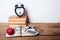 Books, alarm clock, notepad, cellphone and apple on wooden background