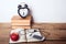 Books, alarm clock, notepad, cellphone with earphones and apple on wooden background