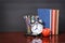 Books, apple, alarm clock and pencils on wood desk table