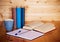 Books, blank notebook, pen and cup of tea on wooden table