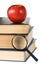 Books, magnifying glass and red apple