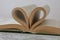 Books pages are twisted as heart sign with Gold ring between them