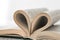 Books pages are twisted as heart sign with wedding ring