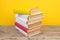Books stacking. Books on wooden table and yellow background. Back to school. Copy space for ad text
