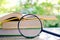 Books zoomed by the magnifying glass on blurred natural green ba