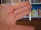 Bookshelf with a lot of german nonfiction literature . Hand in the front . White caucasian hand performs shadow dog pose in front