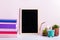 Bookshelf with multicolor books, house plants succulents and black board frame for text. Background for World Book Day. Still life