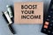 BOOST YOUR INCOME - words on brown paper on the background of a calculator, banknotes and pen