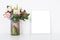 Boquet of flowers in vase by white wall on table with empty fram
