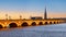 Bordeaux, France. View of Pont de Pierre, old stone bridge over the river Garonne, and Saint Michel cathedral at sunset.