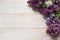 Border of flowers and green leaves of fragrant lilac Syringa vulgaris close-up on a light wooden background.