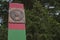 Border post painted in green and red horizontal stripes with a metal plate depicting the coat of arms of the USSR