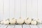 Border of white pumpkins and leaves, white wood background