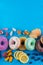 Bordure of colorful fresh donuts with different kinds of topping and fruits on blue paper background.