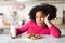 Bored Black Little Girl Sitting At Table With Milk And Cookies