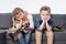 Bored brother and sister sitting on sofa and holding remote control