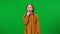 Bored Caucasian teenage girl looking at camera and yawning looking away standing at green screen. Front view portrait of