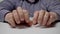 A bored clerk or businessman taps his fingers on the table. Hands of a man in a gray shirt is knocking on the table