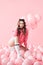 Bored fashionable woman sitting on floor with pink air balloons on pink pastel background