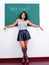 Bored female teacher stands in front of green chalkboard