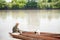 Bored fisherman going fishing with pet, while sitting in rowing old boat at shore in morning.