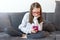 Bored girl sitting on the couch and holding a mobile phone