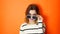 Bored girl with sunglasses in hands on vivid orange background in studio. Young arrogant teenager