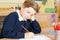 Bored Male Elementary School Pupil At Desk