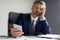 Bored Middle Aged Businessman Sitting At Desk And Holding Smartphone In Hand
