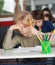 Bored Schoolboy Sitting At Desk In Classroom