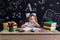 Bored schoolgirl sitting at the desk with books, school supplies ready