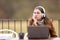 Bored woman with headphones and laptop in a coffee shop