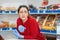 A bored woman in rubber gloves leaned against the counter, waiting for customers. In the background are shelves of the store. The