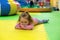 Bored young girl lying on interlocking floor mat in children playgound. Toddler lies on foam mat floor tiles in playroom.