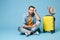 Boring displeased traveler tourist man in yellow clothes isolated on blue wall background. Male passenger traveling