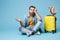 Boring dissatisfied traveler tourist man in yellow clothes isolated on blue wall background. Male passenger traveling